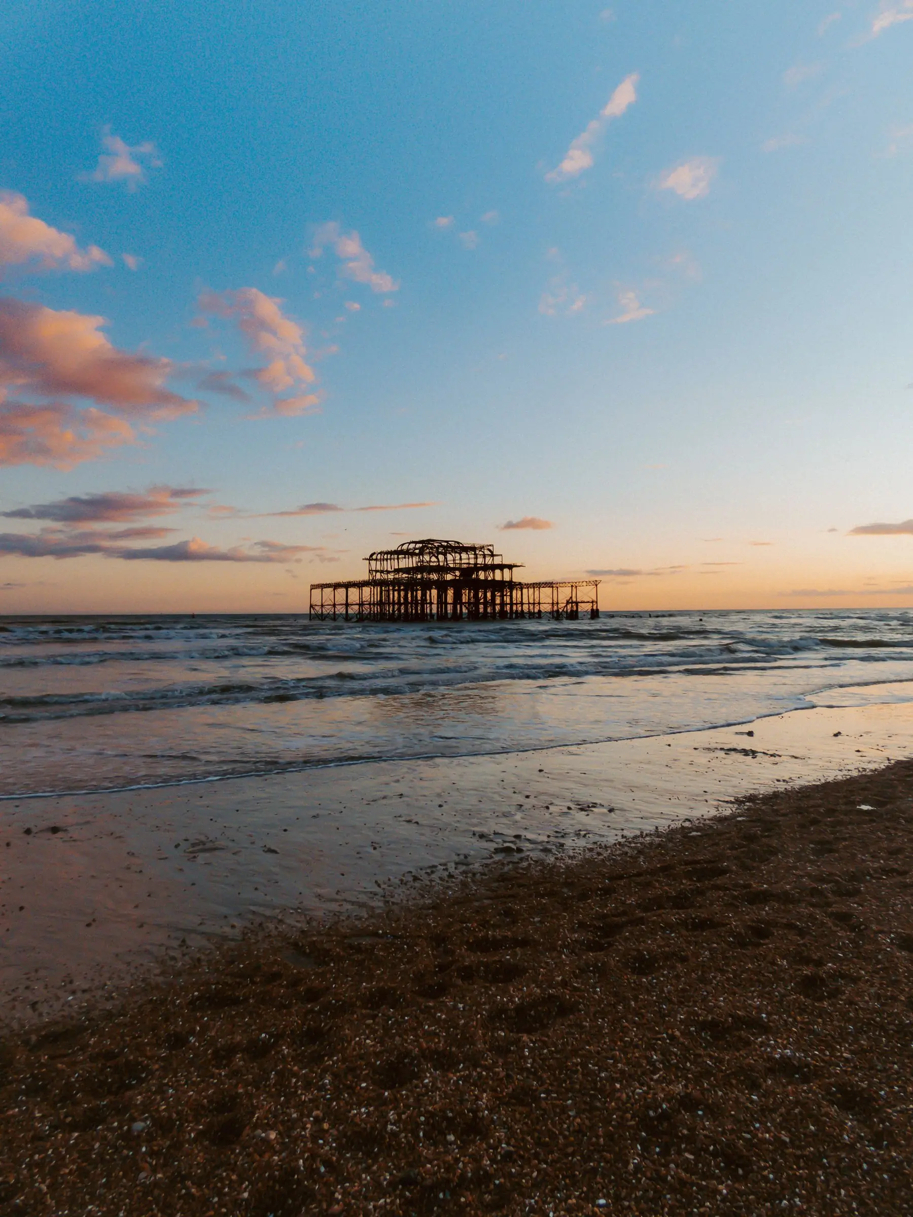 The ruins of Brighton's West Pier at sunset, with a calm sea and an orange sky