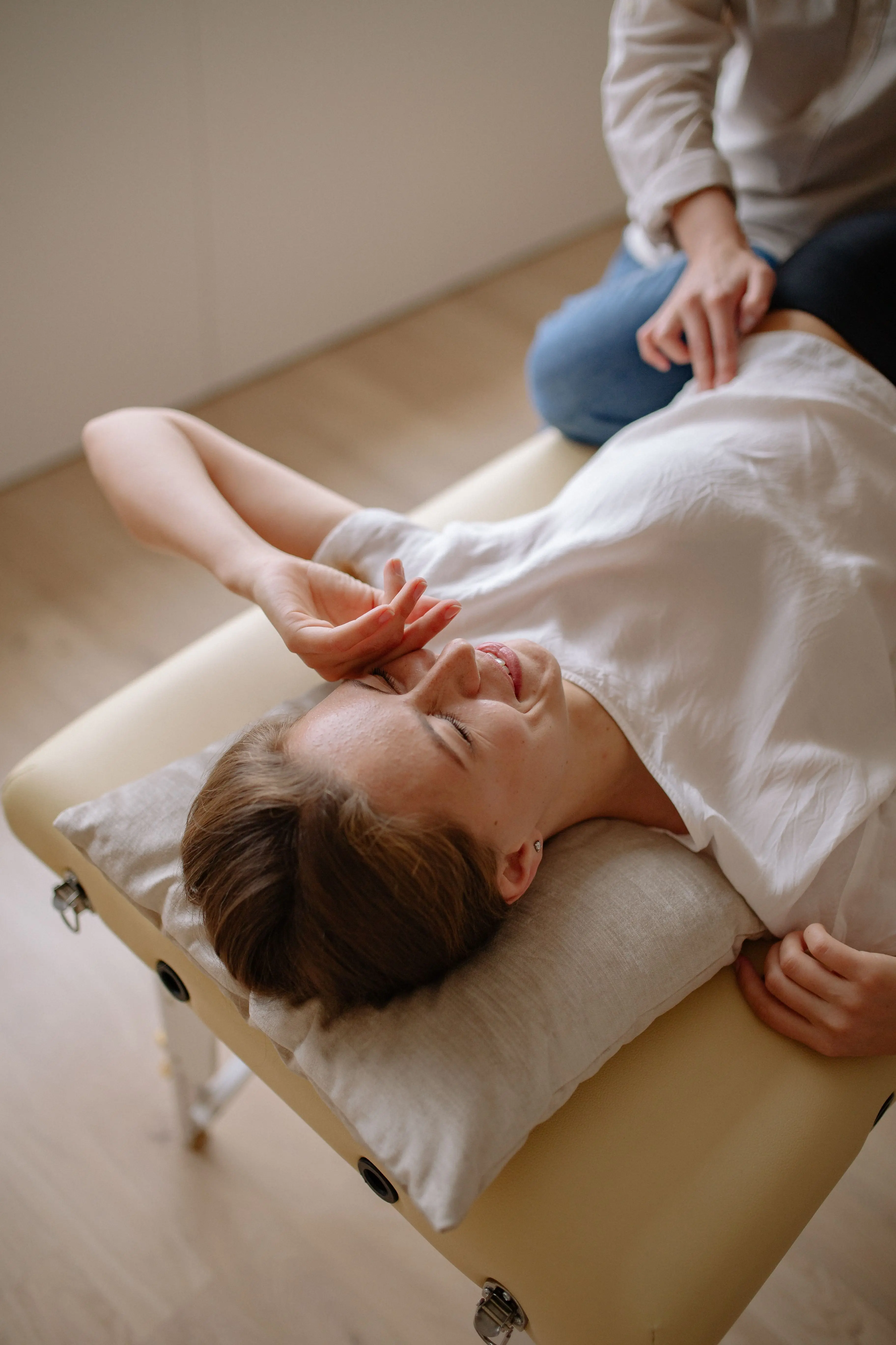 A woman lying on a treatment couch while a physiotherapist works beside her